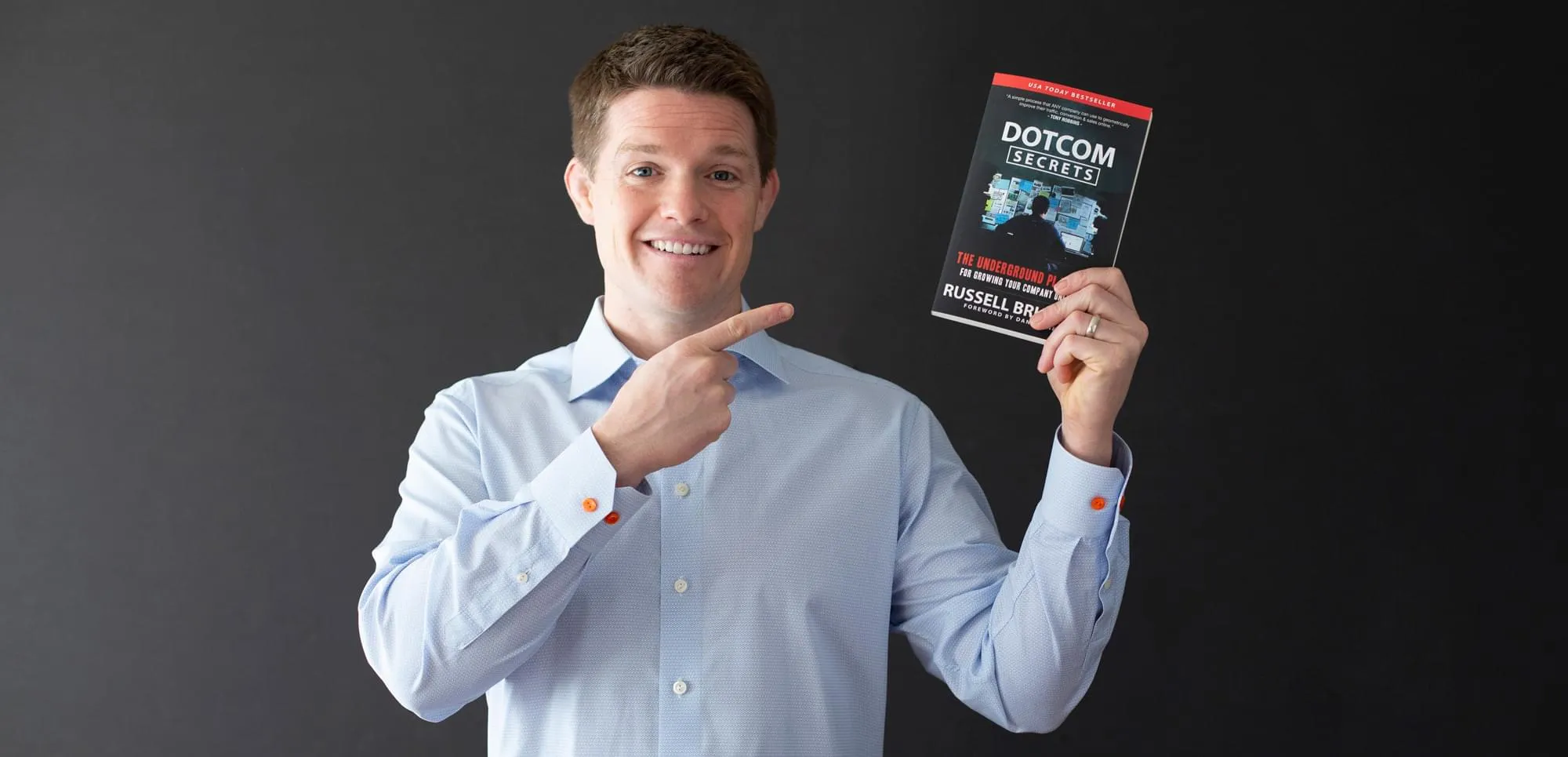 Russell Brunson holding up DotCom Secrets book